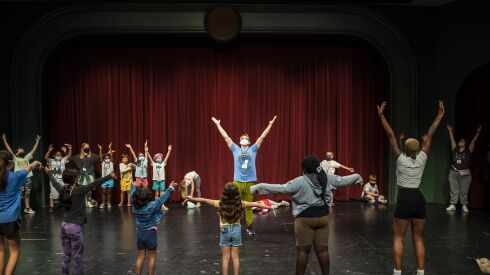 Chazie Bly (center) warms up children at the beginning of the day on July 11 at Hearts to Art, a summer camp for children with parents who have died.