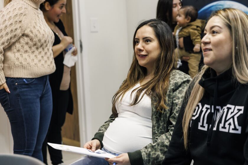 Friends and pregnant mothers, Yuri Cardenas (left) and Yesenia Cruz listen to a talk by a health expert during a communal baby shower held at community organization El Valor on March 29, 2023.