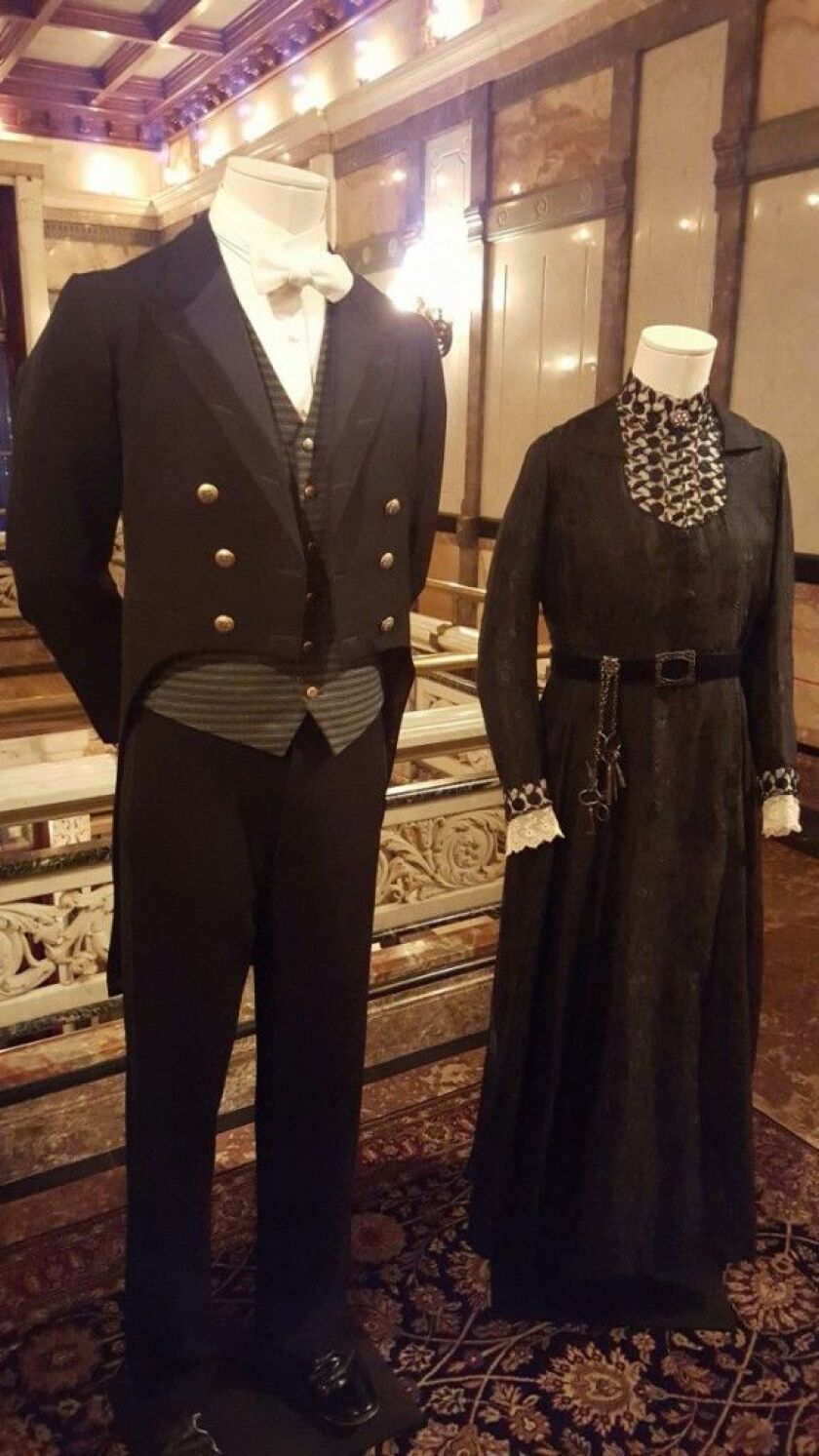Thomas Barrow (Rob James-Collier) and Mrs. Hughes (Phyllis Logan), seasons 1-4. Butler and housekeepers’ uniforms. Her dress: Working outfit of black silk and wool with cream lace trim. His uniform: Footmen’s “liver” made from wool and cotton, with white