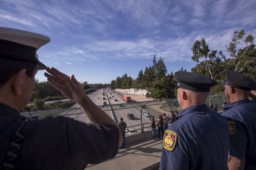 Los Angeles Fire Department Task Force 12 firefighters salute as a procession carries the body of Cory Iverson, 32, a fire engineer for Cal Fire San Diego who died fighting the Thomas Fire, from Ventura to San Diego on December 17, 2017 in Pasadena, Calif
