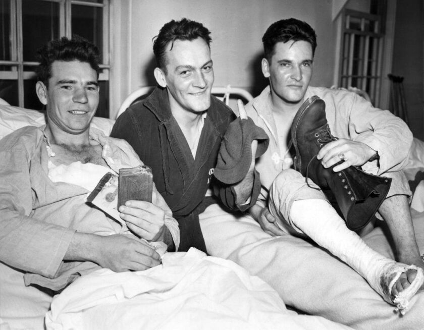 FILE – In this May 28, 1943 file photo, soldiers who took part in the American landing on Japanese-occupied Attu in the Aleutians, from left, Pvt. John E. Terknett, of Eastland, Texas, whose wallet and notebook were ripped by a shell which wounded him acr