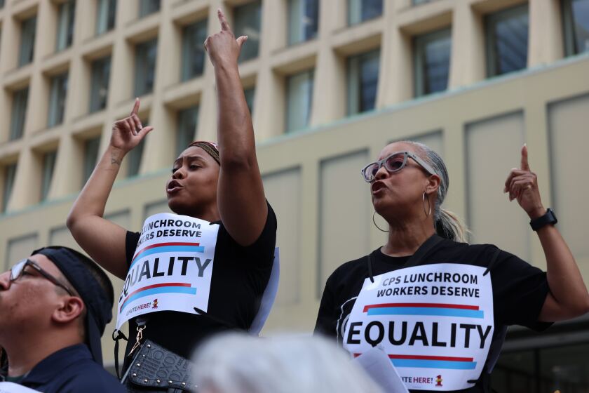 Two people chant at a protest in support of Chicago Public Schools lunchroom workers.