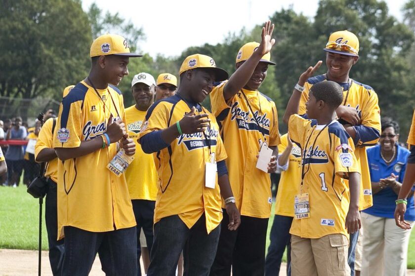 DJ Butler, 12, who plays second base and outfield for the Jackie Robinson West All-Stars, high-fives his teammates at Jackie Robinson Park on Wednesday morning at a rally to celebrate the team’s national championship in the Little League World Series. | A