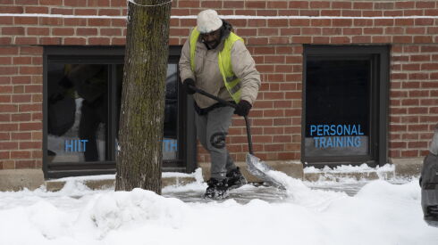 Snow removal worker shoveling the sidewalk on Monroe Street. Monday, January 24, 2022.