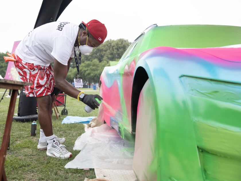A graffiti artist paints a white Ford Mustang at the NASCAR Chicago Street Race on Saturday, July 1, 2023 in Chicago.