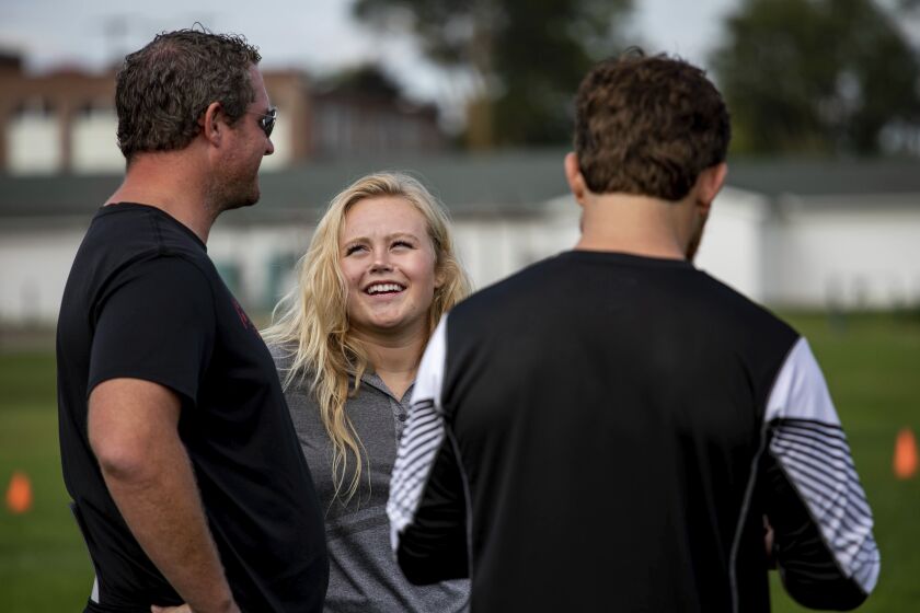 In this Thursday, Sept. 6, 2018, photo former Grand Blanc linebacker and homecoming queen Alicia Woollcott talks with coaches during Grand Blanc High School’s football practice in Grand Blanc, Mich. Woollcott was recently featured in a Nike commercial. (K