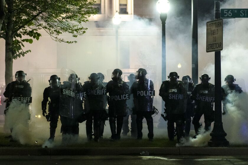 Law enforcement officers advance on protesters in Civic Park in downtown Kenosha through a curtain of tear gas during a protest over the police shooting of Jacob Blake, Tuesday night, Aug. 25, 2020.