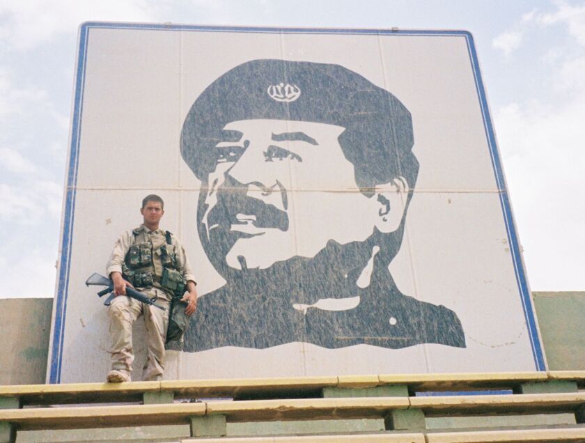 Tyson Manker stands atop Al-Shaab Stadium, overlooking Baghdad. Behind him is a huge image of former Iraqi president Saddam Hussein.