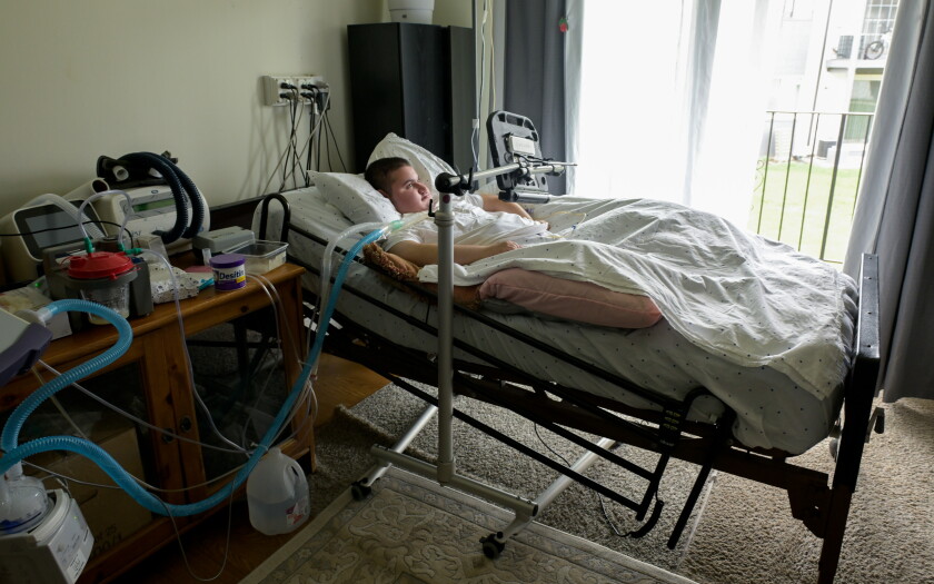 Syrian refugee Omar, 19, in a hospital bed his family's living room.