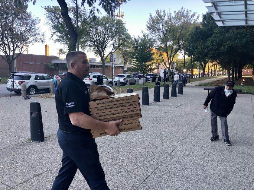 FOP President John Catanzara carries pizzas in to union members at Chicago Police Department headquarters on Monday who were still waiting for their turn to talk to the human resources department to address the city’s COVID-19 vaccine mandate.