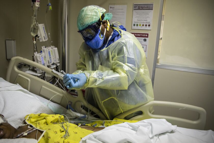 Nurse Tamara Jones checks blood sugar levels for a 73-year-old woman with COVID-19 last fall in the Intensive Care Unit at Roseland Community Hospital.
