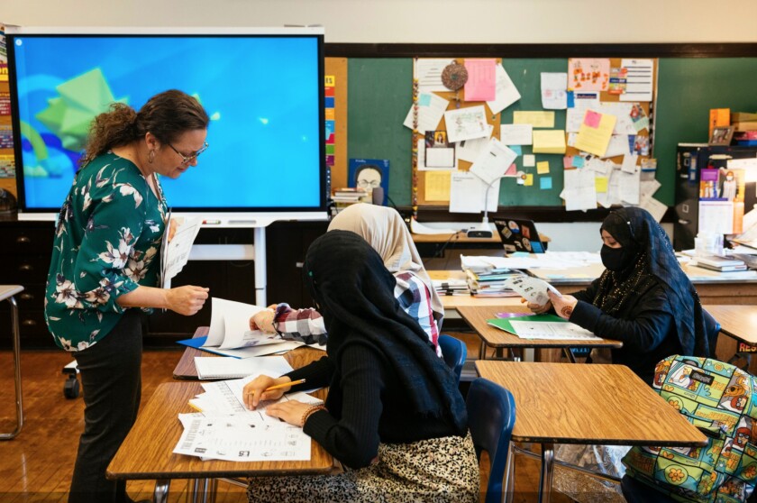 Annmarie Handler (left), an English language teacher, helps students at Sullivan High School in Rogers Park who speak little or no English fill out a bingo board using kitchen vocabulary words.
