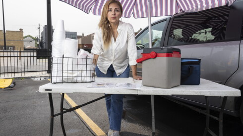 Laura Murillo near 47th Street and Halsted Avenue in Back of the Yards beside her van, folding table, coolers and umbrella. She sells tamales in the neighborhood.