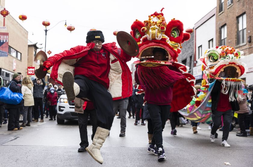 A performer jumps in the air as he performs a dance as the parade makes its way down the street during the Lunar New Year Celebration Parade in Chinatown on Sunday, Jan. 29, 2023.