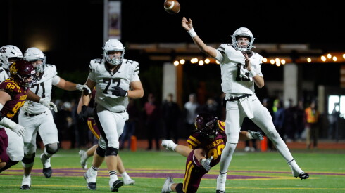 Mount Carmel's Brady Cloherty (13) passes under pressure from Loyola’s Winston Ericson (99).