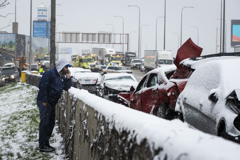 A man talks on his phone on the shoulder of the Kennedy Expressway after a massive pileup crash involving nearly 60 vehicles sent more than a dozen people to hospitals in the inbound lanes of the expressway near North Avenue, Wednesday morning, April 15, 2020.