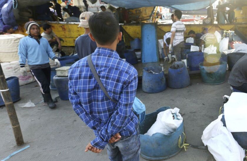 Sulistyo, left, an Indonesian fisherman who was forced to work on a foreign trawler that delivered fish to a Sea To Table supplier, watches local fisherman sort fish at a fishing port in Jakarta, Indonesia. Conscientious consumers, troubled by illegal pra