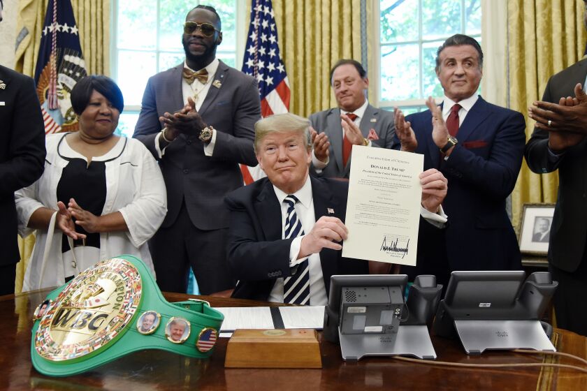 President Donald Trump holds his signed clemency grant for boxer Jack Johnson. Attending the signing (from left) were Johnson’s great-great niece Linda Haywood, Deontay Wilder, Keith Frankel, Sylvester Stallone and Lennox Lewis. | Getty Images