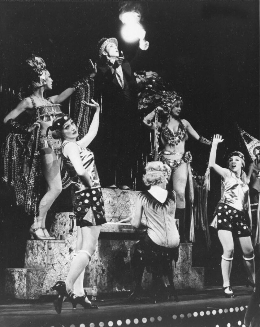 In this Nov. 1966 file photo, Joel Grey, in the role of Master of Ceremonies, stands on the piano during the “Money Song” with the ensemble in the original Broadway musical “Cabaret” at the Broadhurst Theatre in New York. AP Photo, File