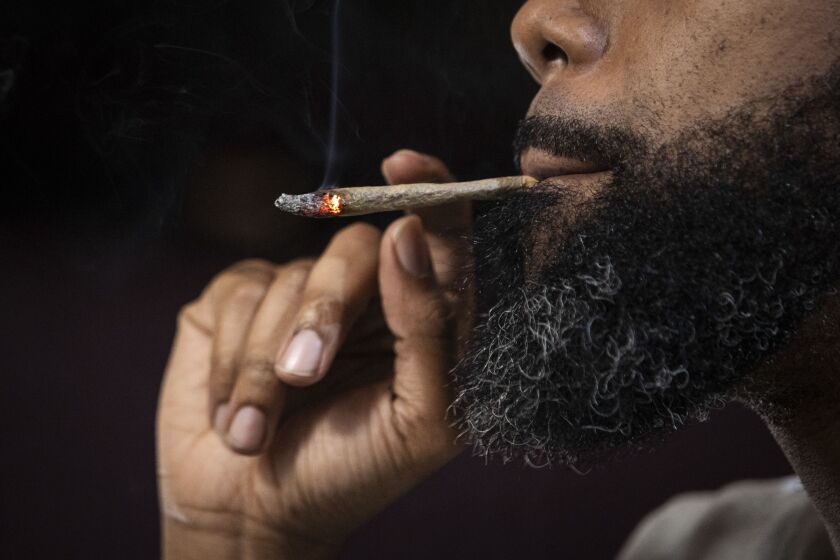 Cannabis consultant Mike Malcolm smokes a joint in a North Side home as he explains what customers can expect at dispensaries now that recreational marijuana is legal in Illinois, Jan. 8, 2020.