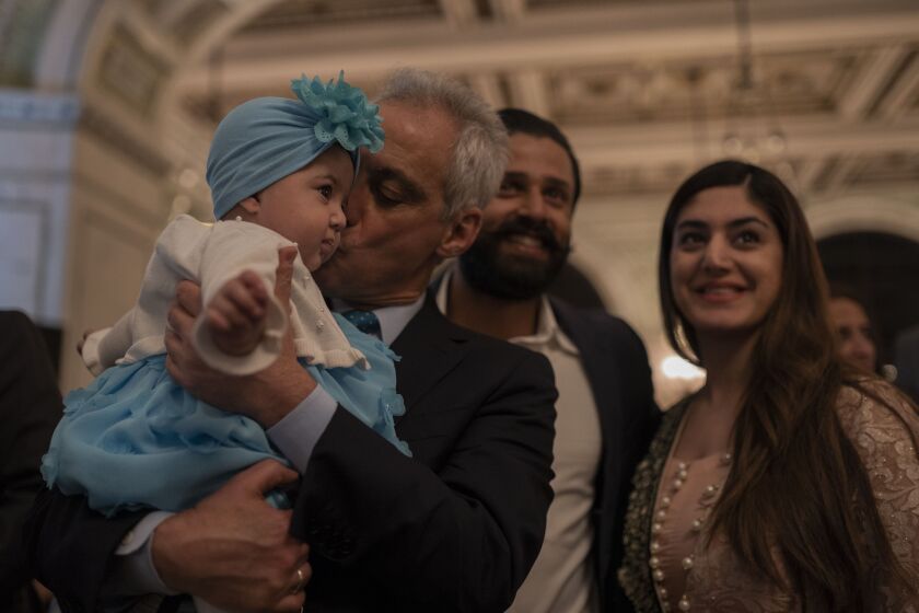 Mayor Rahm Emanuel kisses a baby as he meets people at the annual iftar meal at the Chicago Cultural Center on May 7, 2019. | Pat Nabong/For The Sun-Times