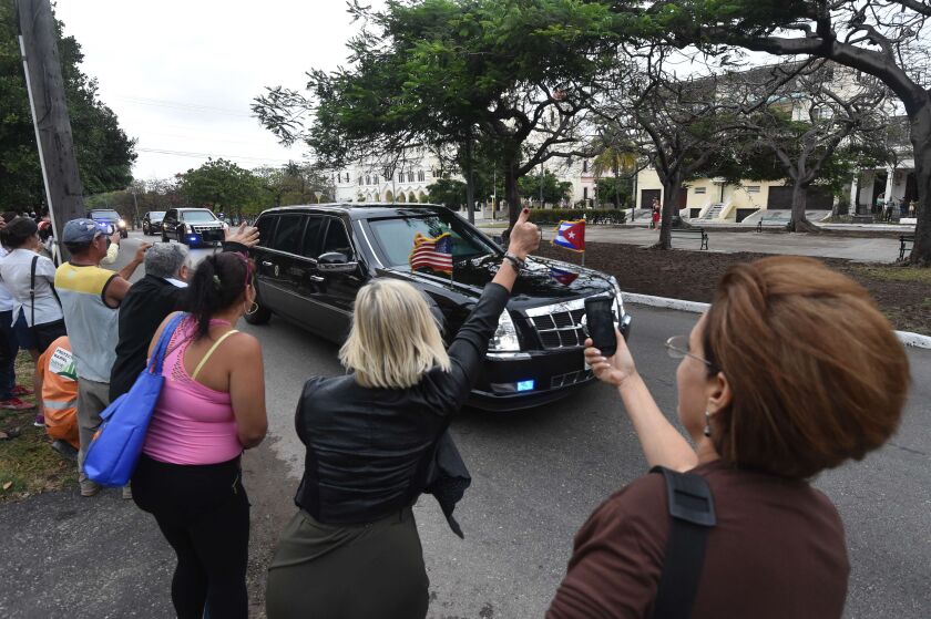 Cubans wave and take pictures as U.S. President Barack Obama’s car passes by on its way to Revolution square in Havana on Sunday. Obama will hold rare talks with his Cuban counterpart Raul Castro on Monday in Havana, setting aside a more than half-centur