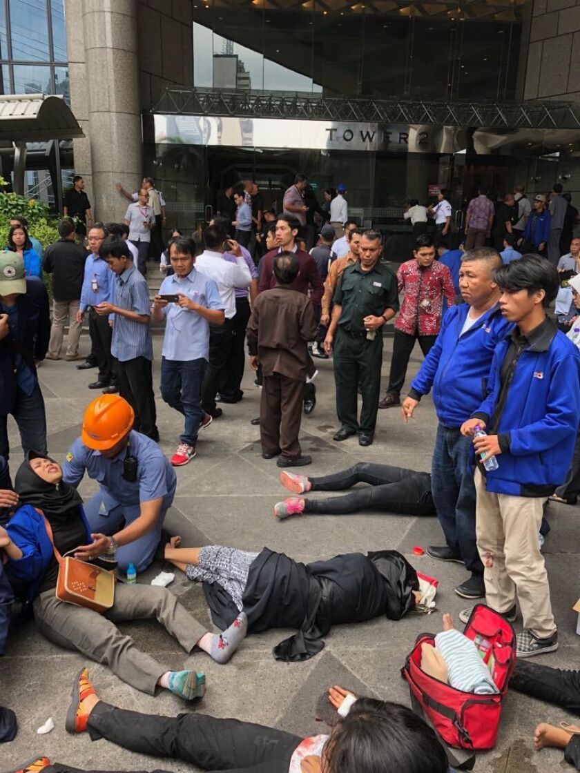 An Indonesian worker attends one of evacuated victims after a structure inside the Jakarta Stock Exchange tower collapsed in Jakarta, Indonesia, on Monday. | AP photo
