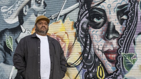 Angel Silva stands in front of two Catrinas that appear in his mural on the side of a West Lawn supermarket.