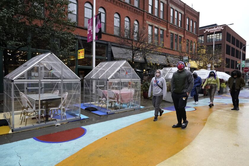 People walk by outdoor plastic dining bubbles on Fulton Market in Chicago in October 2020.
