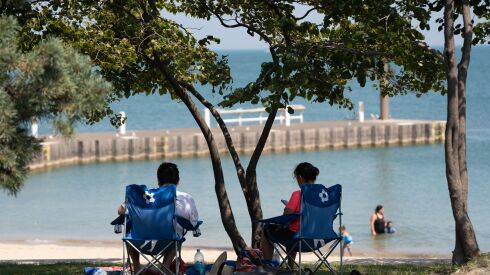 Los residentes se sientan bajo la sombra en la playa 31st Street Beach mientras estaba vigente una advertencia de calor excesivo el miércoles, 23 de agosto de 2023.