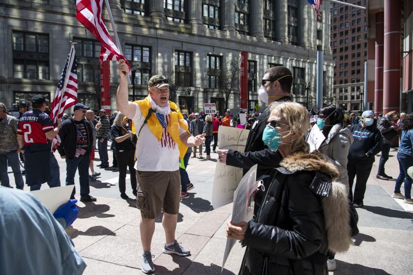 A Reopen Illinois protester confronts a group of medical professionals who gathered and silently counterprotested,