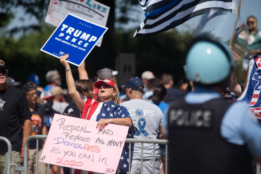 Chicago police officers keep watch as a pro-police protester and supporter of President Donald Trump shouts at counter-protesters during the “Defend the Police” rally in Grant Park, Saturday afternoon, July 25, 2020.