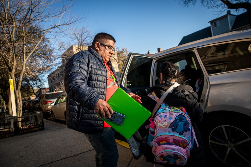 Baltazar Enriquez helps kids get into a van to take them home outside of St. Agnes of Bohemia School in Little Village on Nov. 14. It’s one of several community-led efforts that sprang up this fall to help children get to and from school safely as immigration enforcement activities intensified in Chicago.