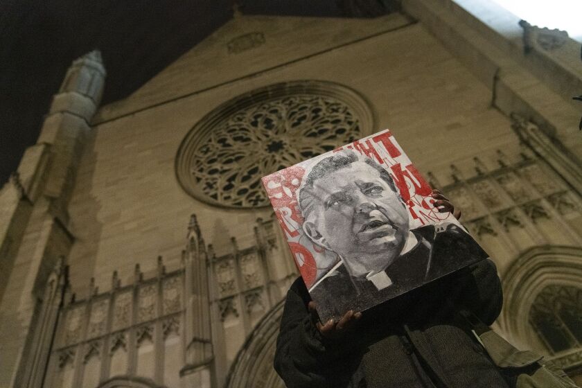 A woman holds up a painting of Father Michael Pfleger outside the front of St. Sabina’s during a rally for Father Pfleger.