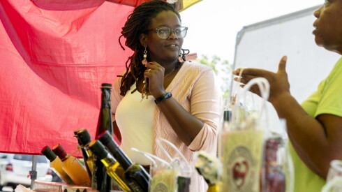 Customer Chelsa Moore, who said she feels safer buying fresh produce from farmers markets, speaks to a vendor at Pullman Farmers Market in Pullman on Wednesday, July 15, 2026.