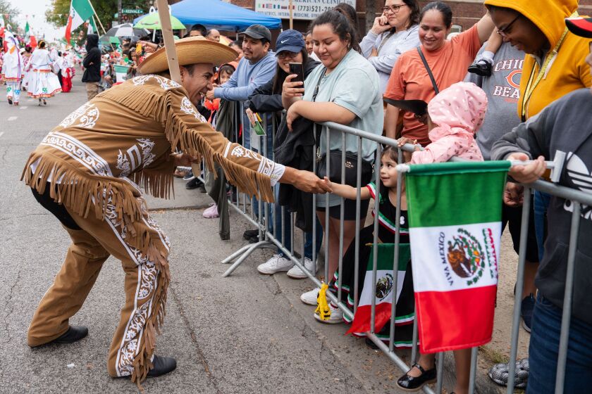 A parade goer shakes hands with children during the Mexican Independence Day Parade along 26th Street in the Little Village neighborhood, Saturday, Sept. 16, 2023. | Pat Nabong/Sun-Times