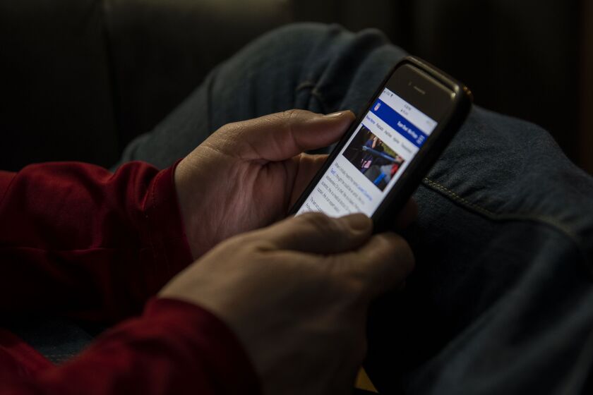 A man who asked that he only be identified as Anthony reads news about the Super Bowl on his phone Friday.