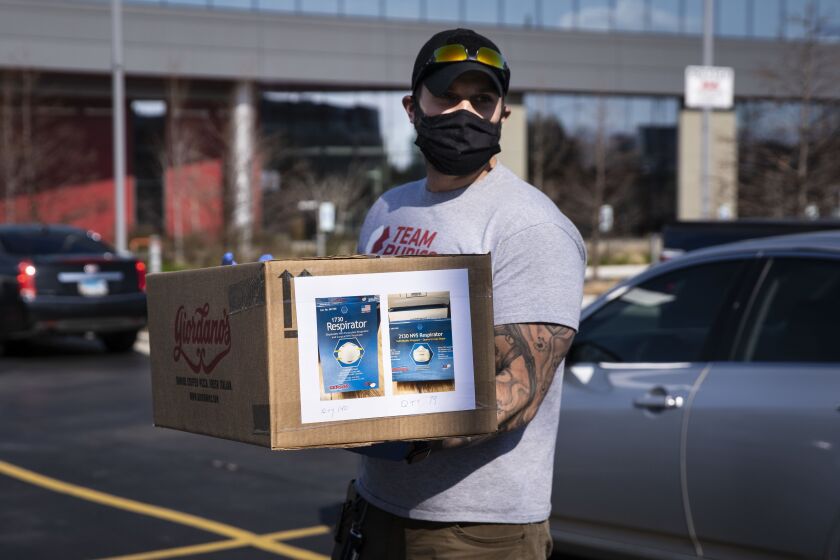 Kazimieras Urbonavicius wears a cloth face mask as he volunteers at a personal protective equipment drive at the United Center.