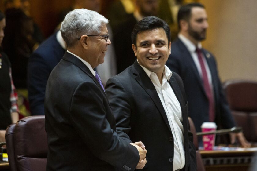 Ald. Byron Sigcho-Lopez (25th) (center), shakes hands with Ald. Roberto Maldonado (26th) before a City Council meeting in 2019.