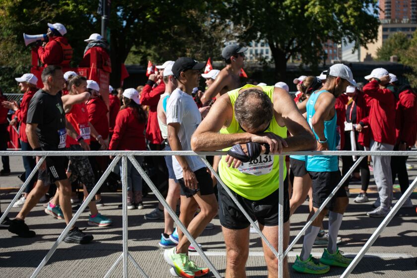 A runner rests after crossing the finish line along South Columbus Drive near Grant Park during the 2022 Bank of America Chicago Marathon. In 2021, the number of racers dropped to 26,109 because of pandemic restrictions.