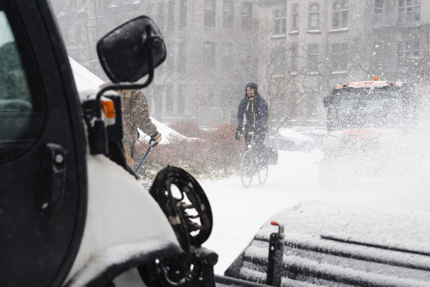 2025年2月12日水曜日、歩道から雪が除去されると、ハイドパークのシカゴ大学のジョセフ・レーゲンシュタイン図書館を通り過ぎるサイクリスト。パットナボン/サンタイム