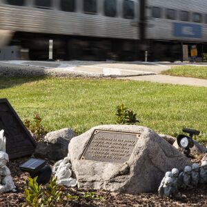 An outbound Metra train travels past a memorial at Algonquin Road and Northwest Highway in Fox River Grove, Wednesday afternoon, Oct. 21, 2020. On Oct. 25, 1995, inbound Metra train No. 624 crashed into a school bus at that intersection, killing seven teenagers and injuring the bus driver and 24 passengers.