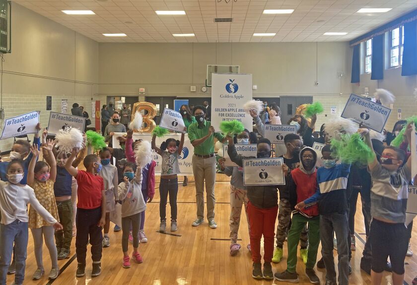 Teacher Reggie Spears (green shirt) surrounded by some of his students at Bronzeville Classical Elementary School after being surprised with his Golden Apple award on Thursday, May 13, 2021.