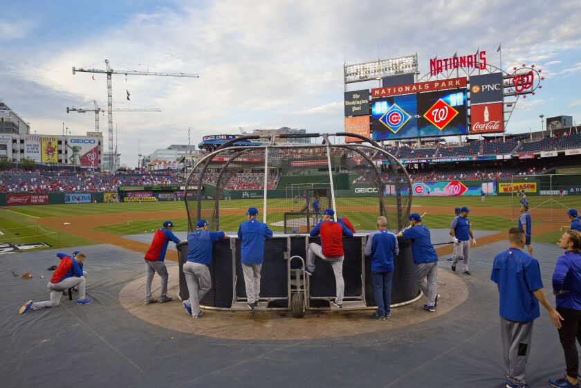 Joe Maddon, center, watches his team take batting practice.