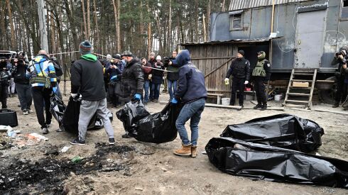 City workers carry body bags with six partially burnt bodies found in the town of Bucha on April 5, 2022, as Ukrainian officials say over 400 civilian bodies have been recovered from the wider Kyiv region, many of which were buried in mass graves.