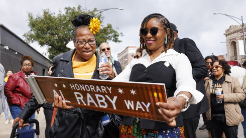 Katanya Raby, right, granddaughter of Al Raby, holds a sign dedicated to the late civil rights leader.