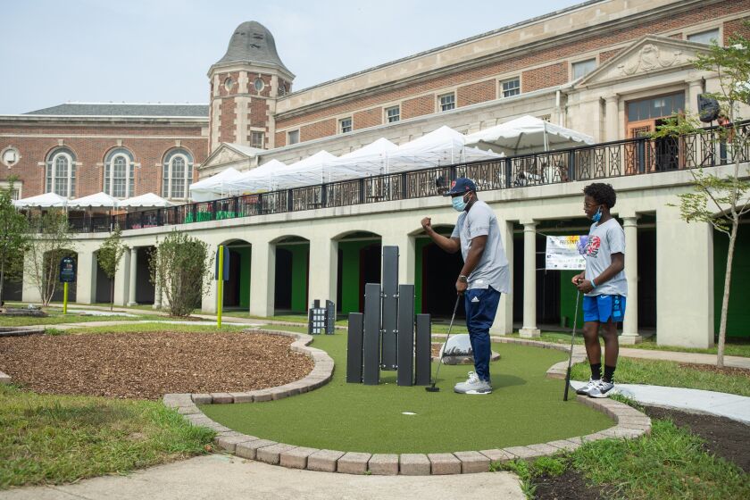 Khalid Hannah and his son Khalil play mini golf on the opening day of the Douglass 18 mini golf course in the North Lawndale neighborhood Saturday.