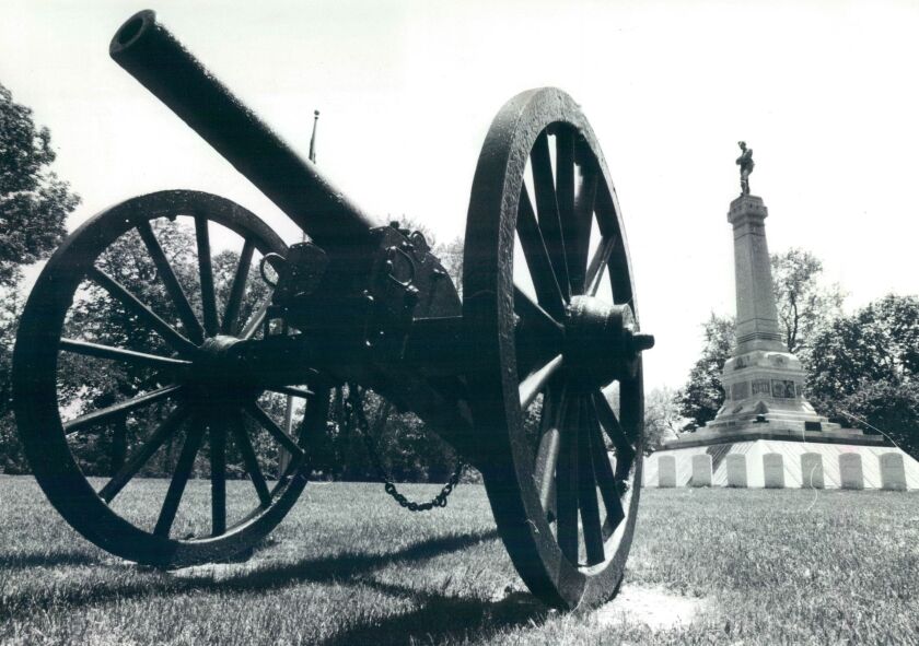 Civil War cannons stand near a 30-foot monument topped by a statue of a soldier, marking a mass grave of Confederate soldiers in Oak Woods Cemetery. | File photo