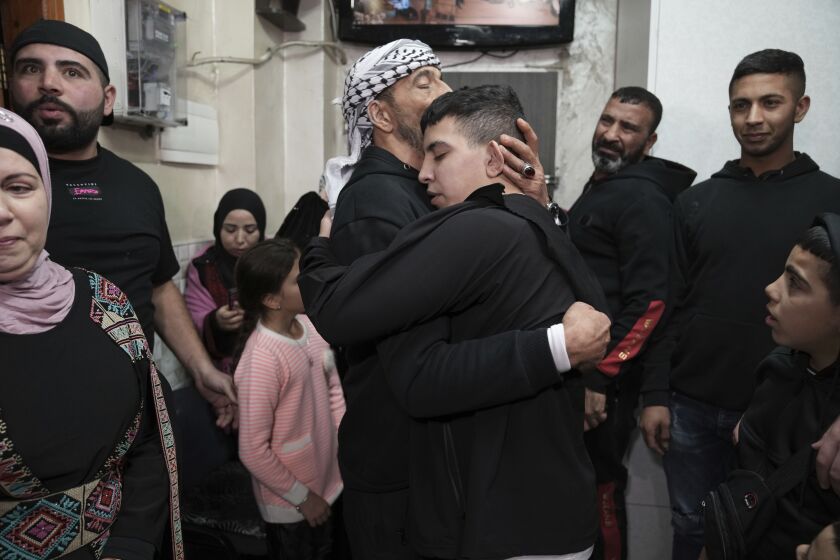 Ahmed Salaima, 14, center, a Palestinian prisoner released by Israel, is hugged by his father as he arrives home in the east Jerusalem neighborhood of Ras al-Amud on Nov. 28, 2023.