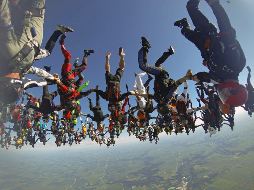 In this photo provided by Mickey Nuttall, members of an international team of skydivers join hands flying head-down to build their world record skydiving formation Friday, July 31, 2014, over Ottawa, Ill. It took the team 13 attempts to to build the forma
